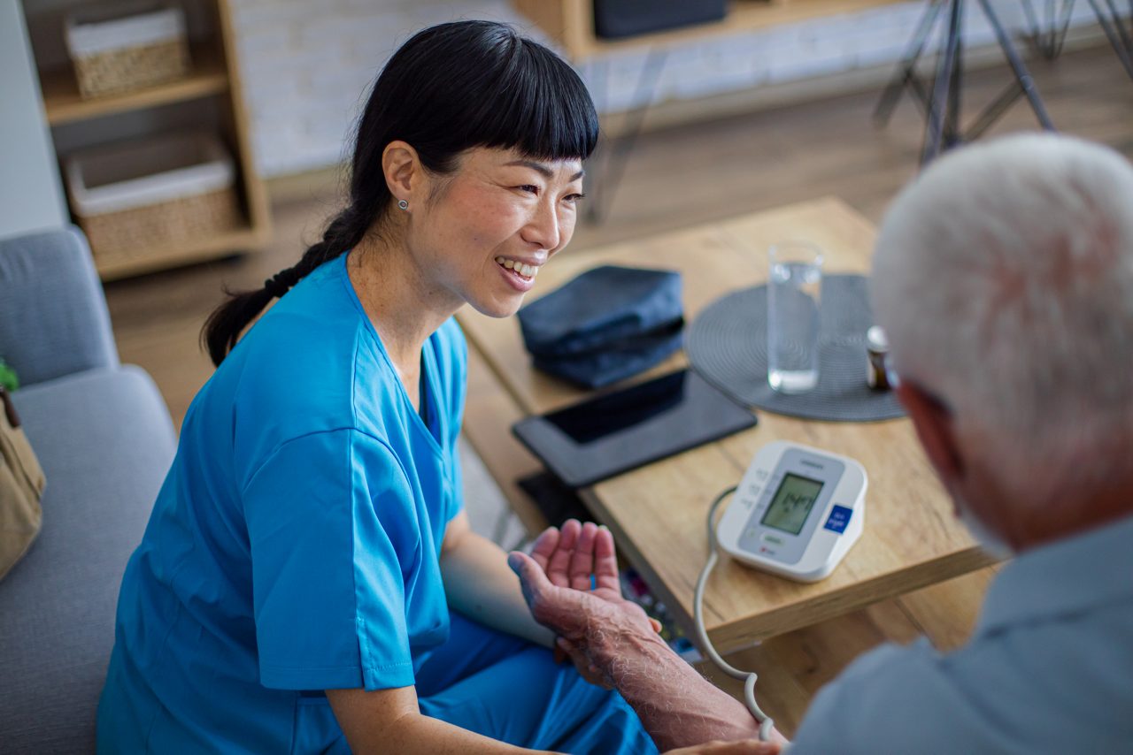 Healthcare professional measuring senior man's blood pressure at home