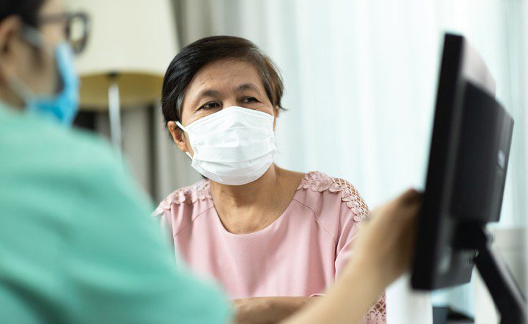 Patient with mask looks at computer screen