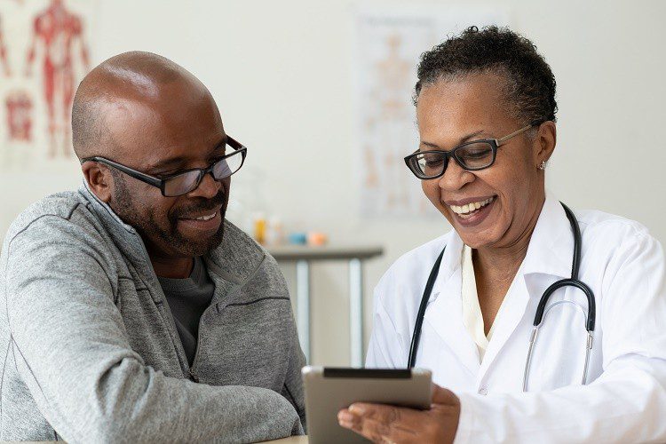 Two stylized figures in medical attire discuss an abstract framed image. The setting conveys a professional and collaborative atmosphere.