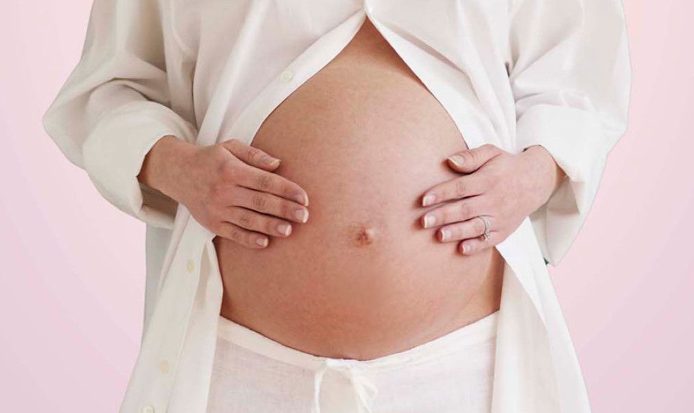 Women holding her lower abdomen.