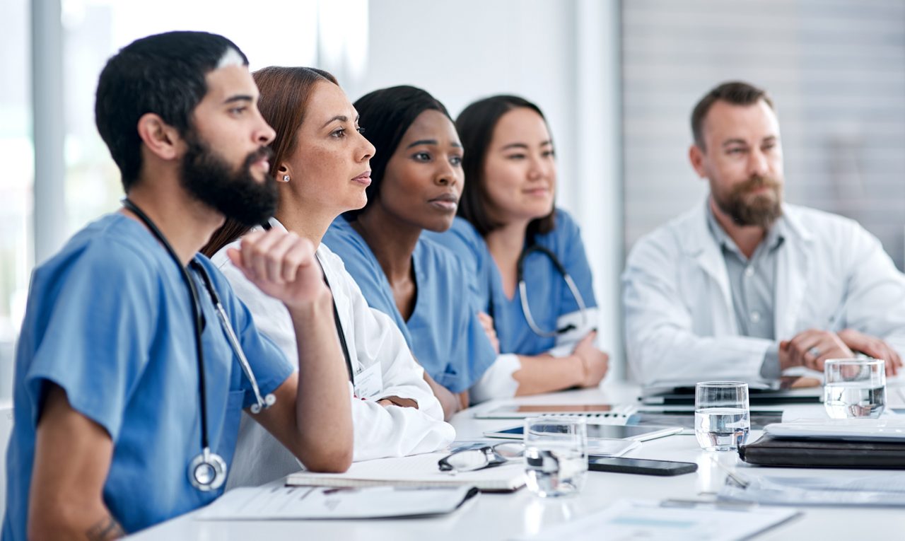 Shot of a doctor sitting alongside her colleagues during a meeting in a hospital boardroom