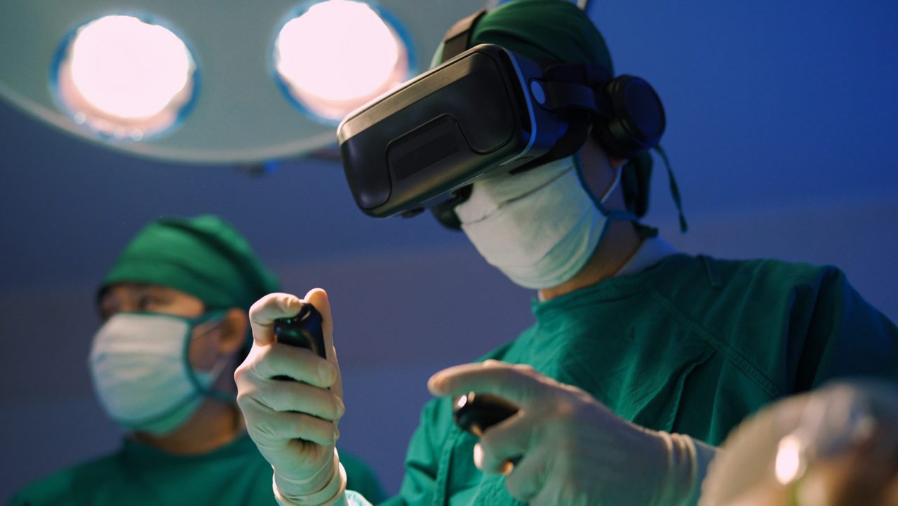 Professional surgeons in  uniform and VR headset performing operation on patient in modern clinic.