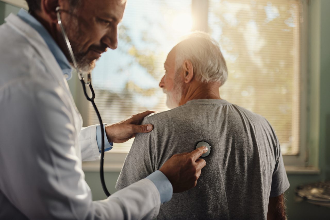 Doctor listening to man's heart.