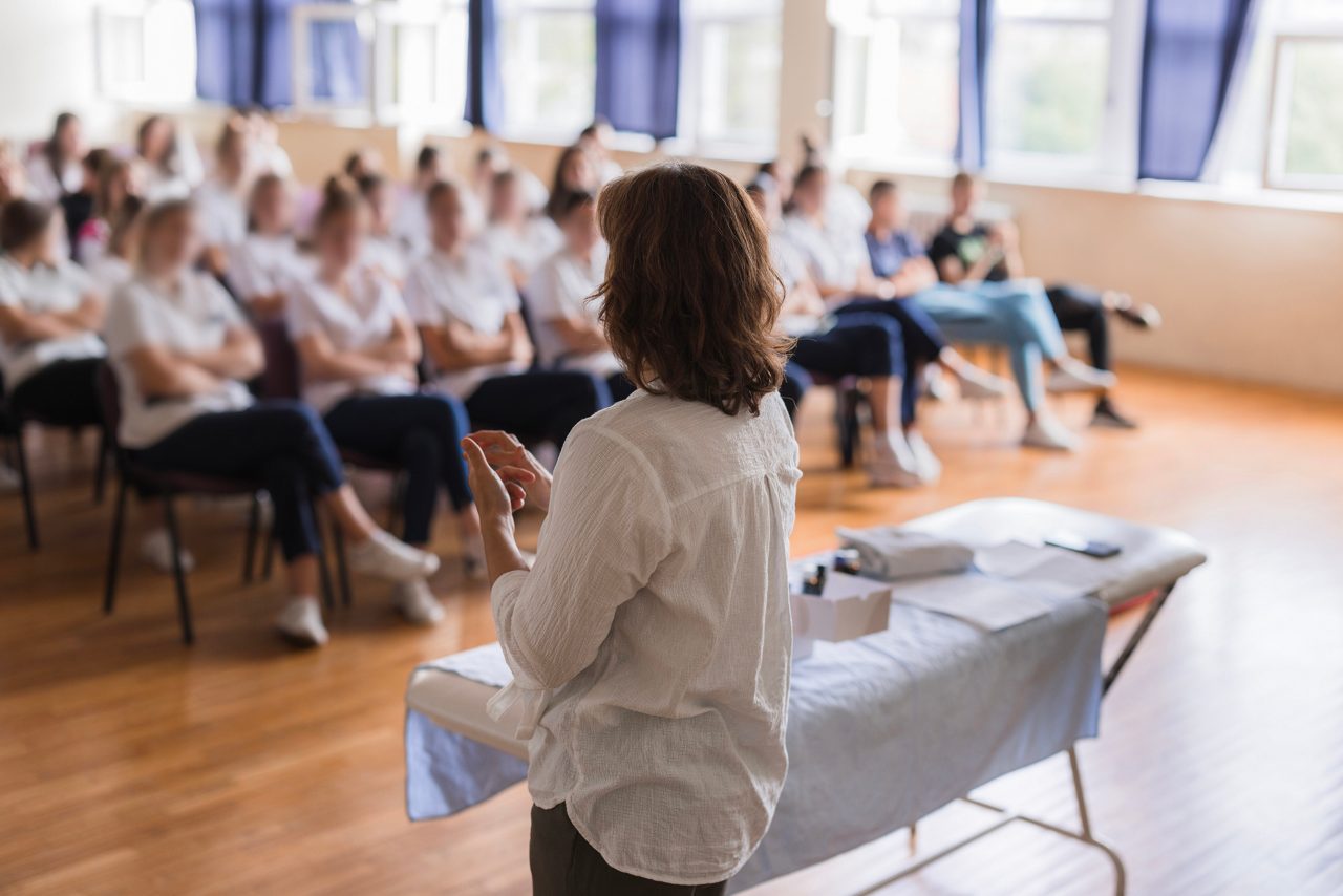 A speaker leads a workplace health presentation for a group of employees.