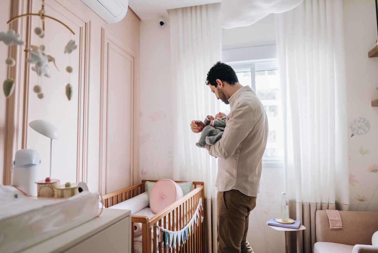 Father holding his newborn daughter at bedroom