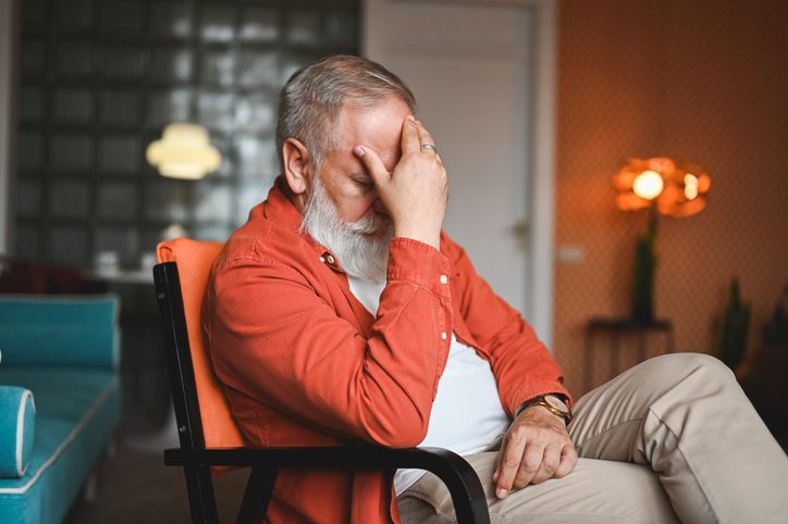 Worried senior man sitting on chair.