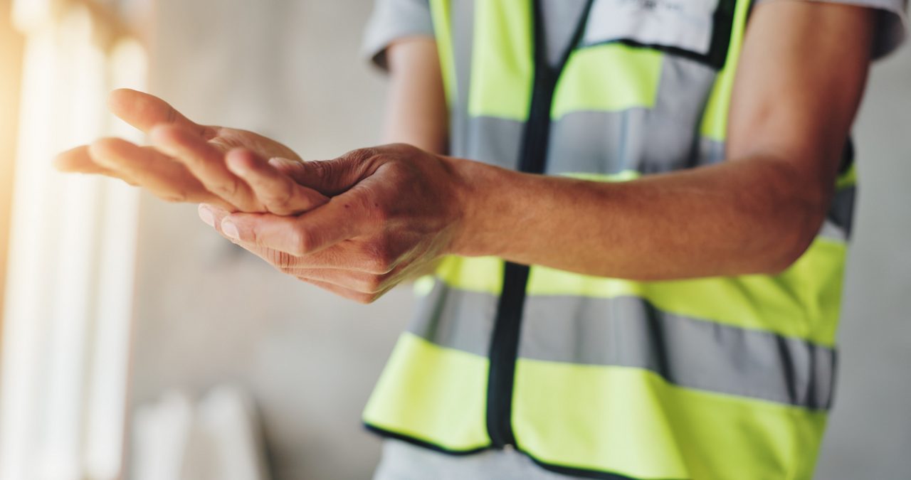 Hands, construction worker and pain with carpal tunnel for renovation project, arthritis or injury at site. Person, engineer and builder with burnout, muscle fatigue or tired with massage for relief