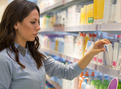 A woman picking out sunscreen from a store shelf