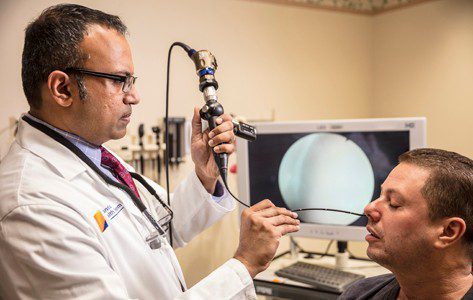 Dr. Tom Thomas, head and neck cancer specialist, examines a patient's nasal passages.