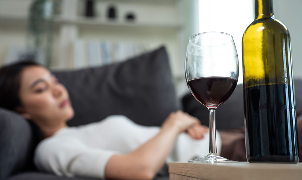 A woman sleeping next to a glass of wine