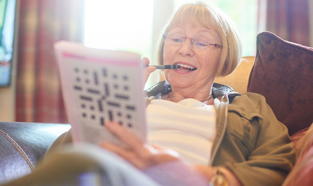 A senior woman playing a newspaper game.