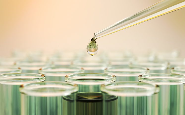 Pipette dropping liquid into tube.