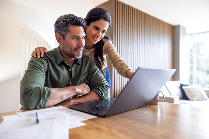 Woman helping man on laptop is shown.