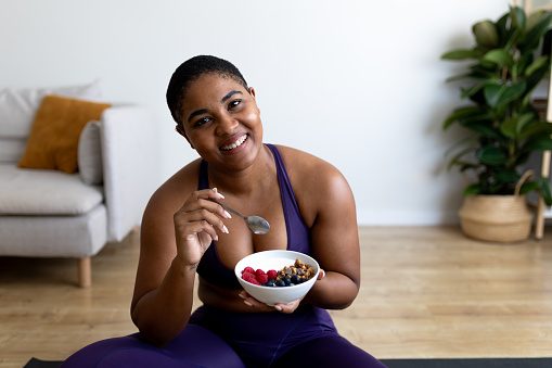 Women sitting down eating granola and fruit bowl