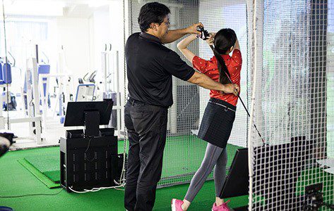 A golf coach helping a girl practice her swing.