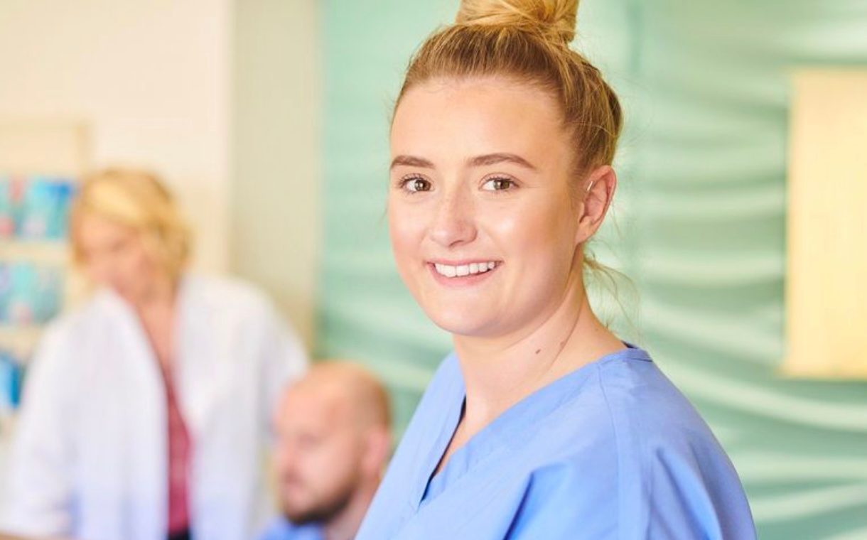 Woman in scrubs smiling.