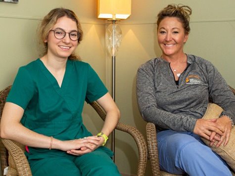 Two healthcare workers sitting and smiling.