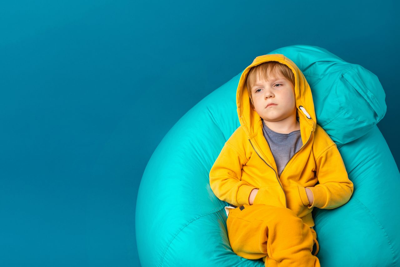 Concept of mental health and depression in schoolchildren and preschoolers. Child toddler sad and apathy sit on bean bag.