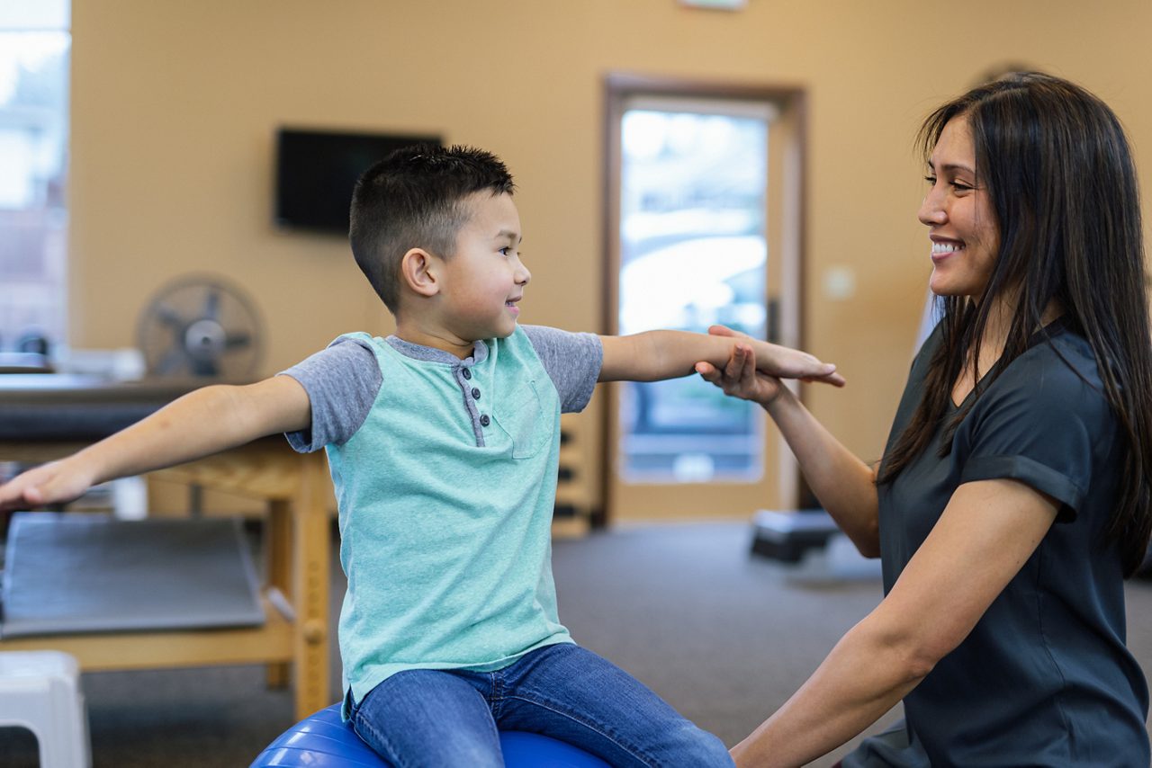 A physical therapist helps a young boy.