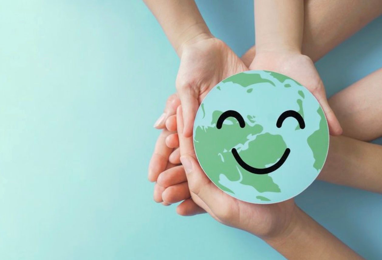 People holding a smiley face of planet Earth.