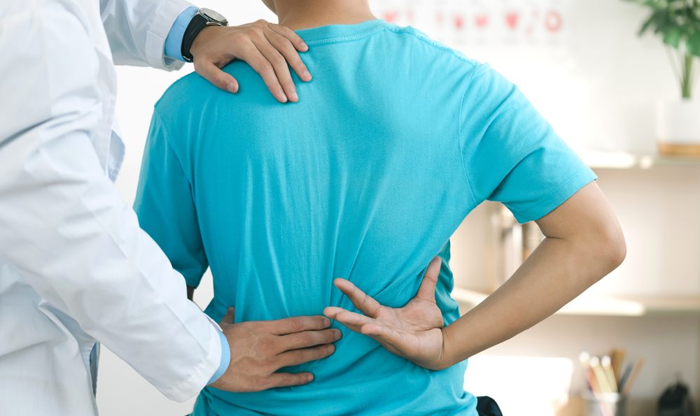Doctor palpates a man's painful lower back.
