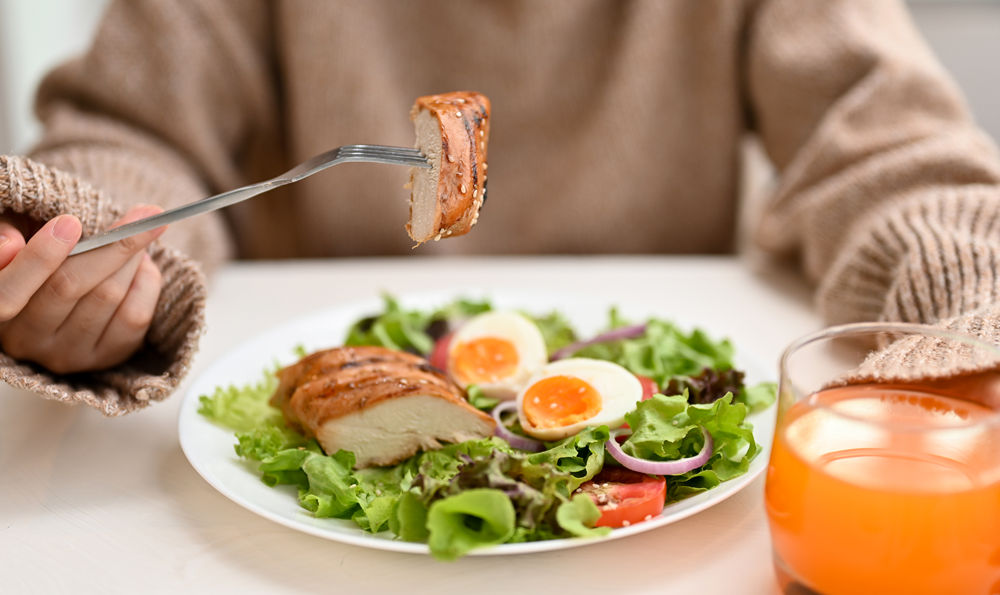 A woman eating a chicken and egg salad