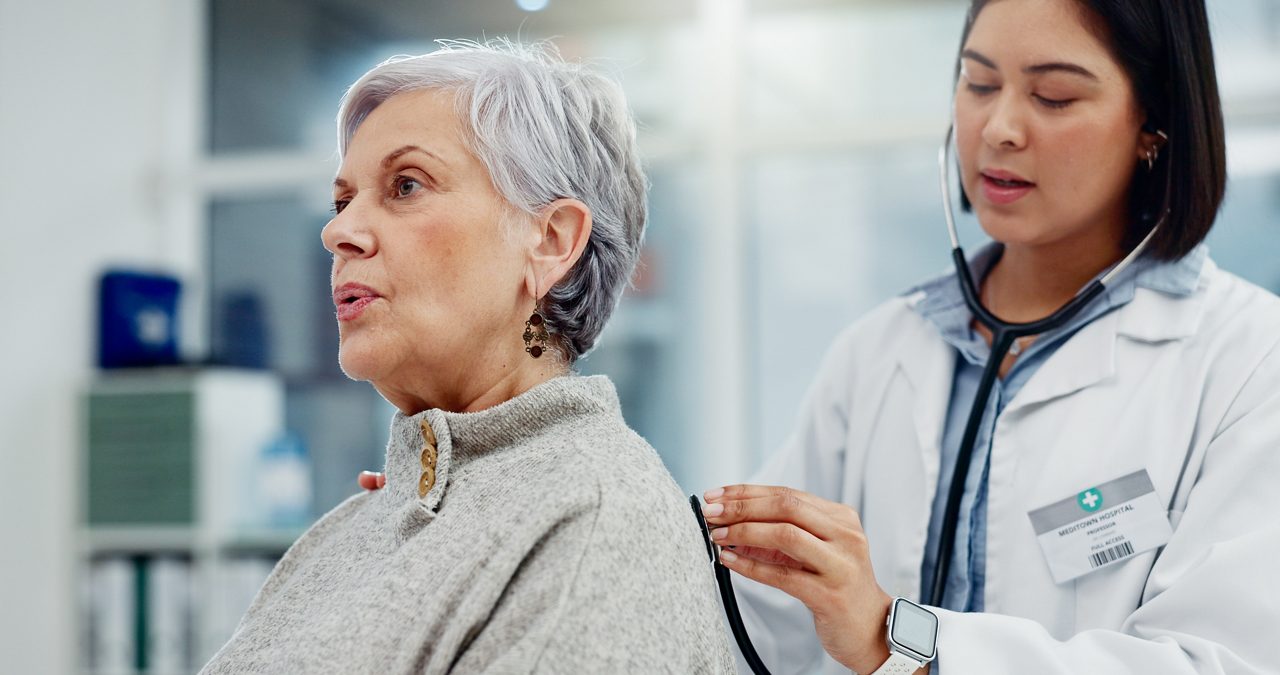 Doctor placing stethoscope on patient's back.