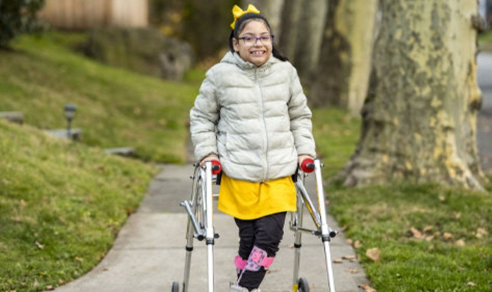 Seven-year-old Samantha E. walking down the sidewalk with help of a walker