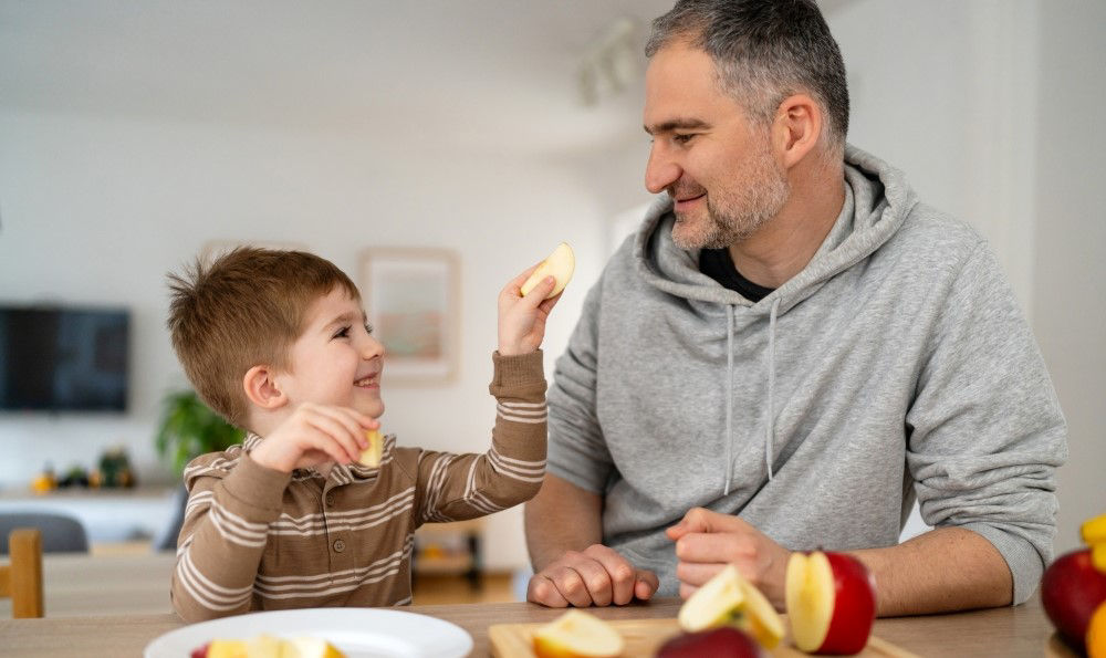 Son giving his dad an apple slice.