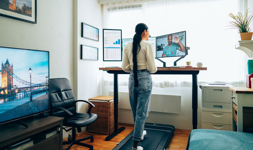 Woman working at standing desk while on a walking pad.