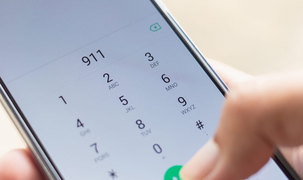 A hand dials 911 on a cell phone.