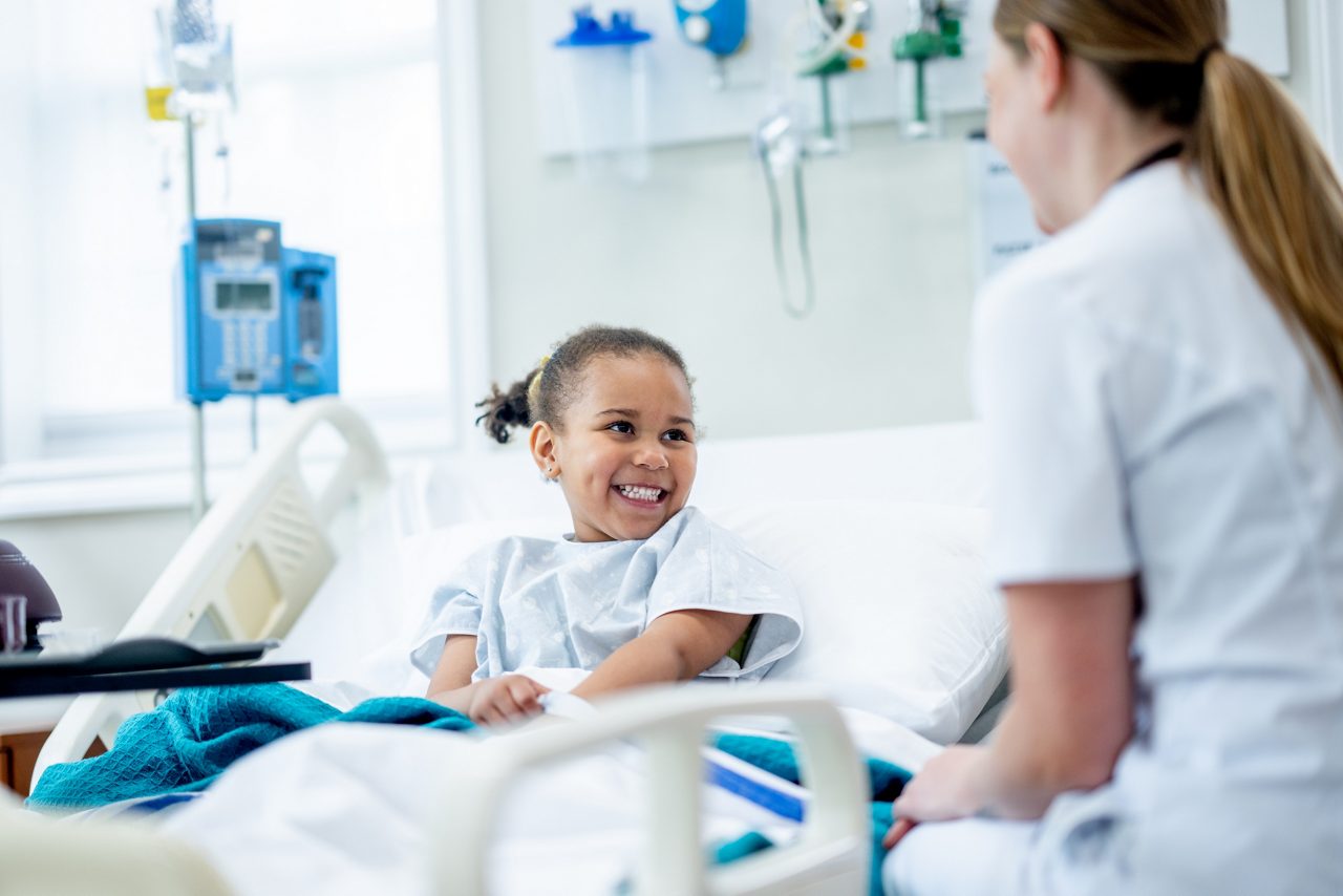 Pediatric surgery patient smiling at nurse.