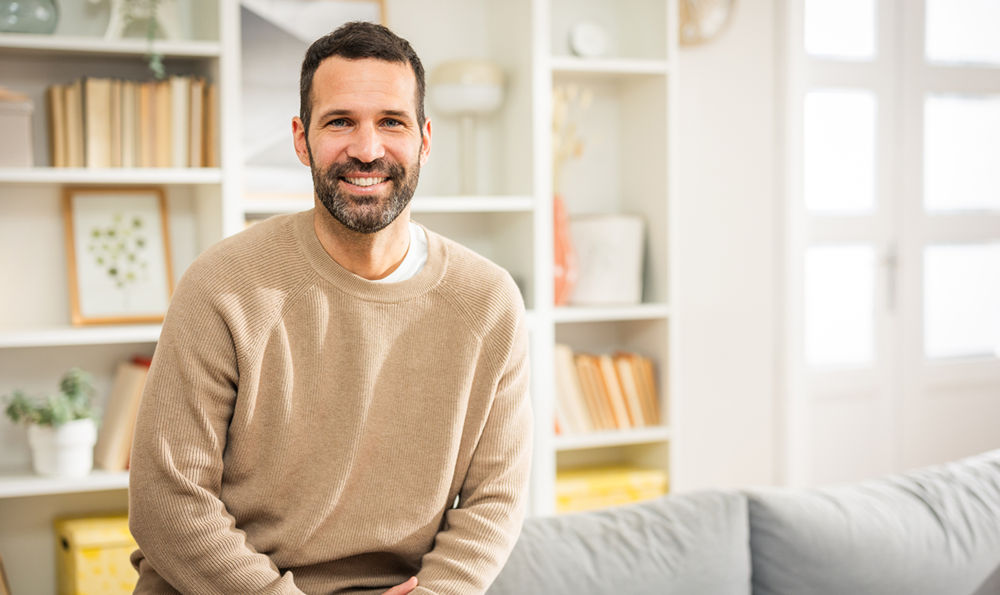 Man smiling and sitting on the couch.