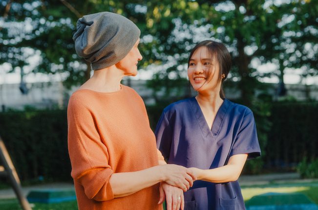 Cancer patient walking outside with caregiver.